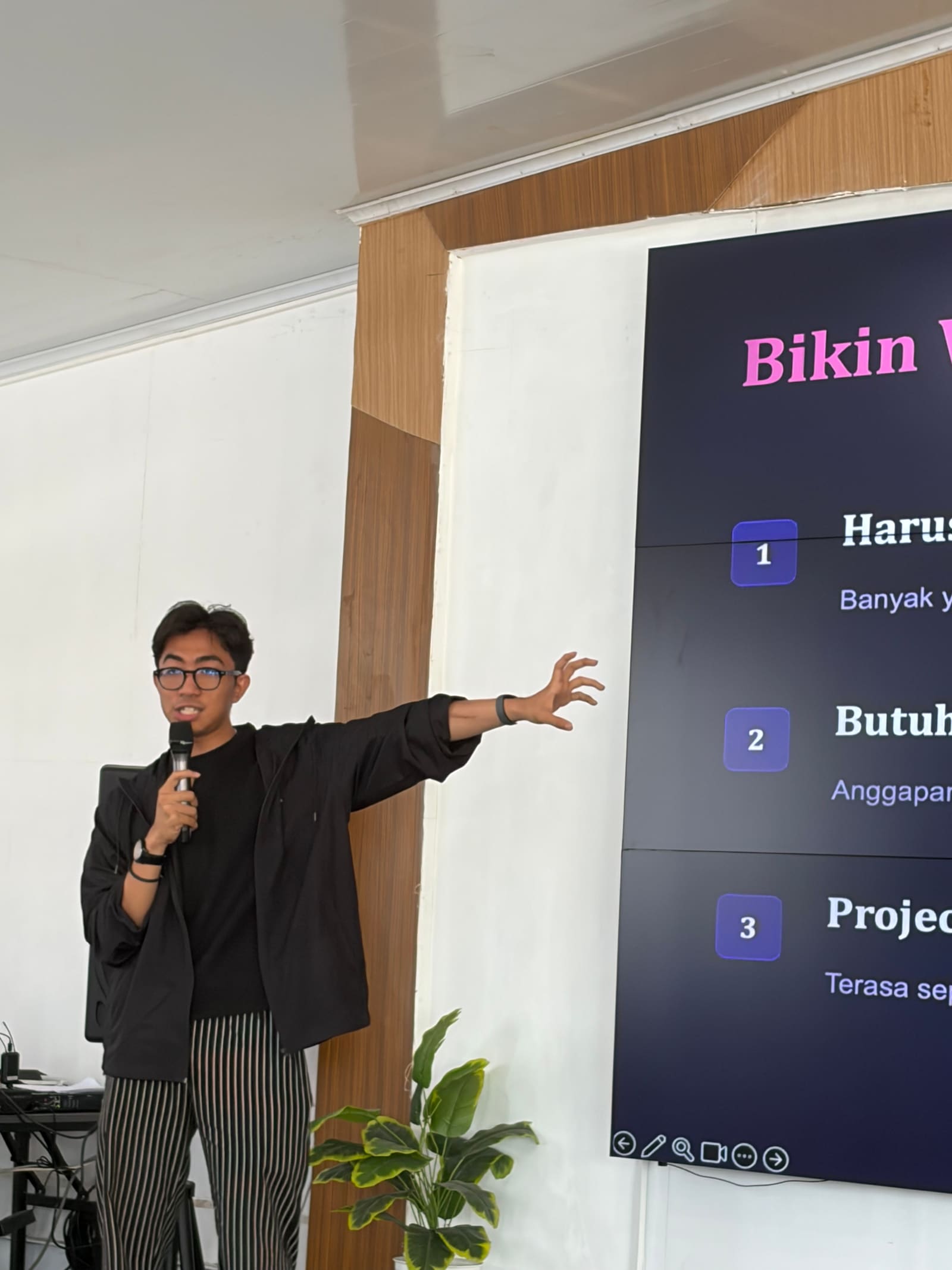 Fahmi Fahreza menjelaskan materi Batch 3 sambil mengangkat tangan, dengan slide anggapan seputar pembuatan website di belakangnya