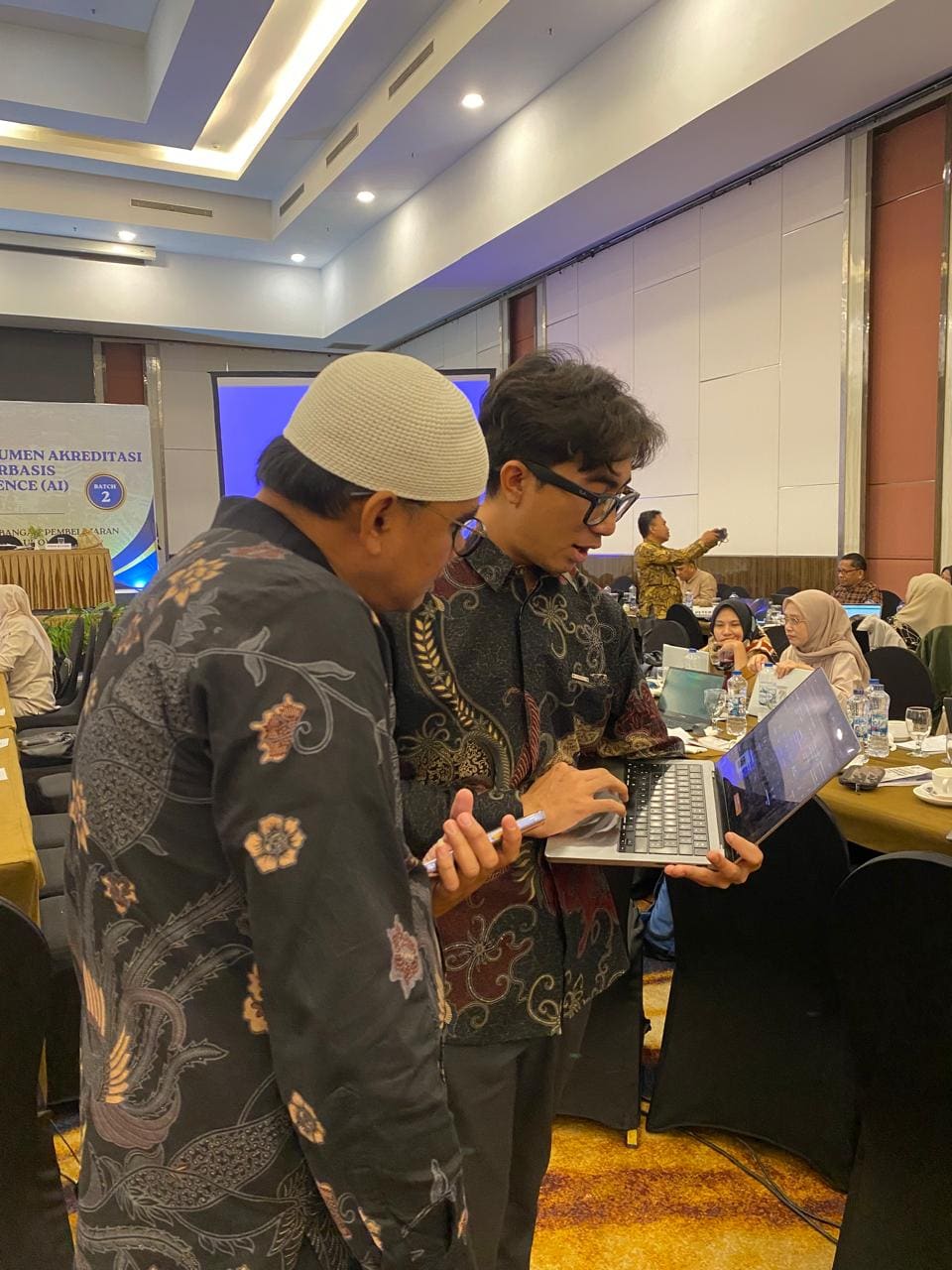 Fahmi Fahreza assisting a lecturer at their laptop during the hands-on session at Universitas Halu Oleo