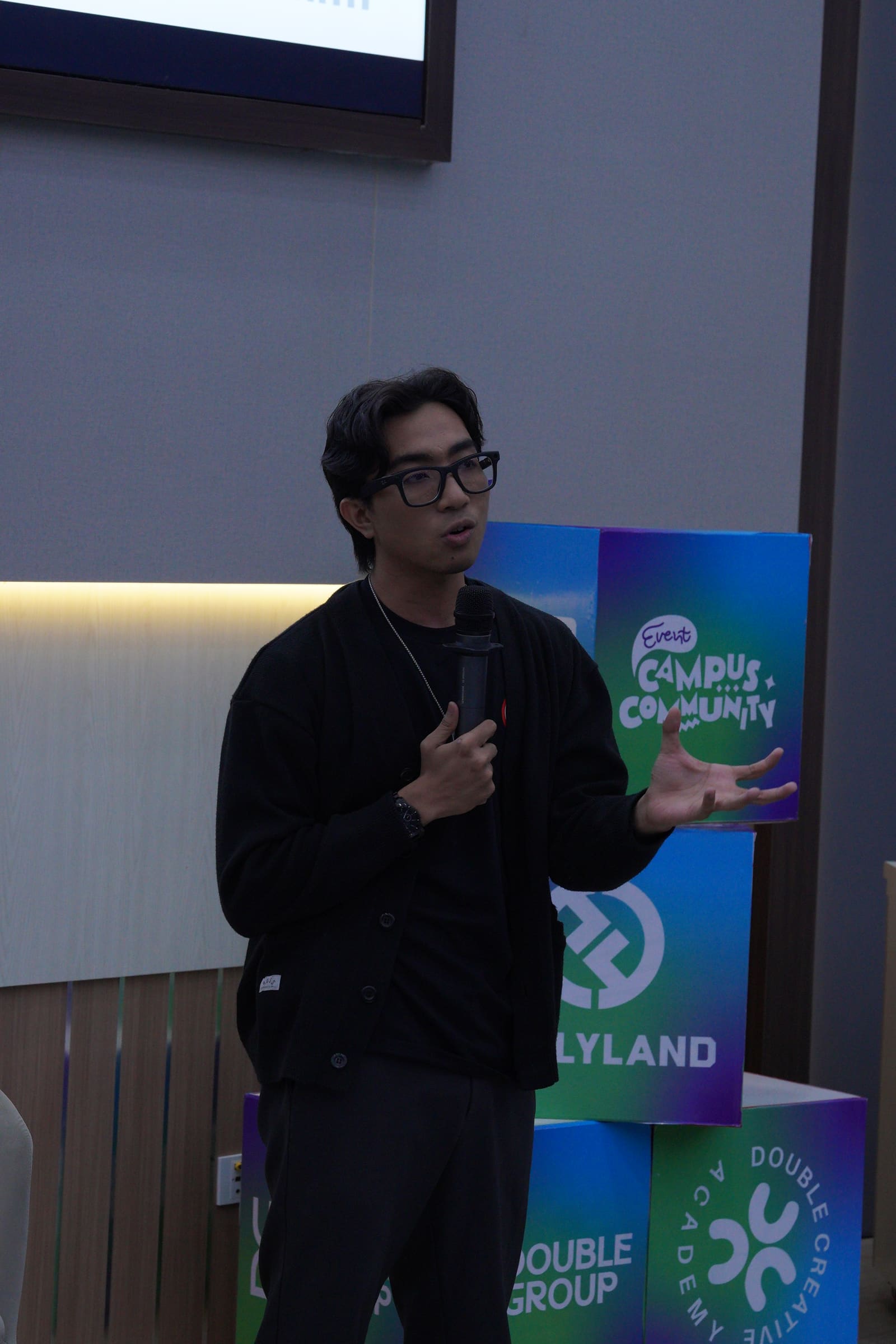 Fahmi Fahreza speaking in front of the Campus Community branding cubes at the Universitas Hasanuddin session